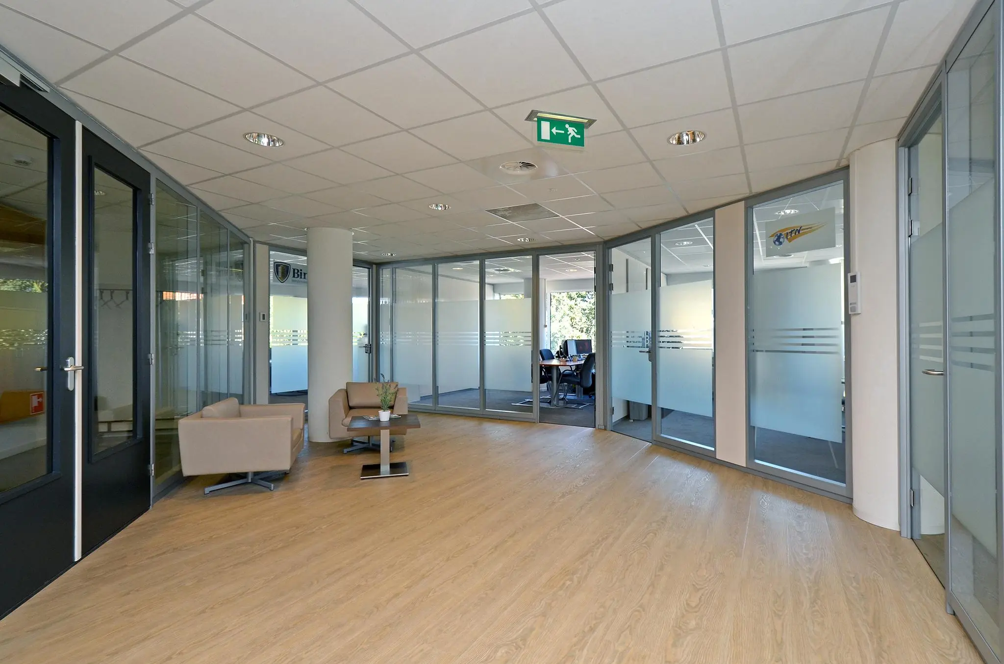 Moderne kantoorruimte aan de 1e Hogeweg met glazen vergaderruimtes, zithoek en houten vloer.